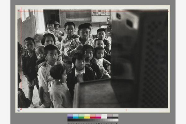 Children gathered in front of a television whose back faces the camera; the supplied print reproduction includes a colour scale.