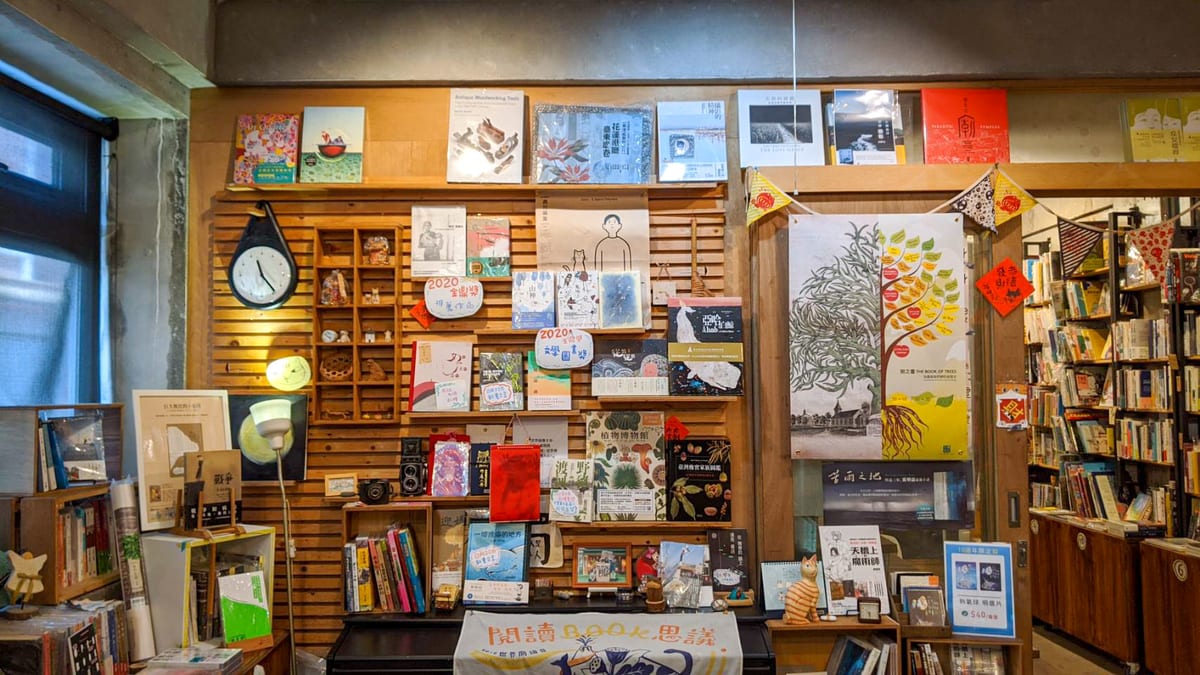 A wooden book display with face-out books, cameras, handwritten cards and a cat-shaped clock.