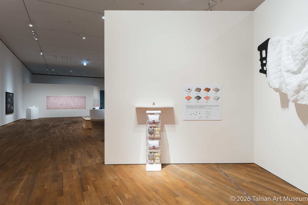 A capsule-toy machine stands in the foreground of the gallery, where visitors can obtain small objects from it.