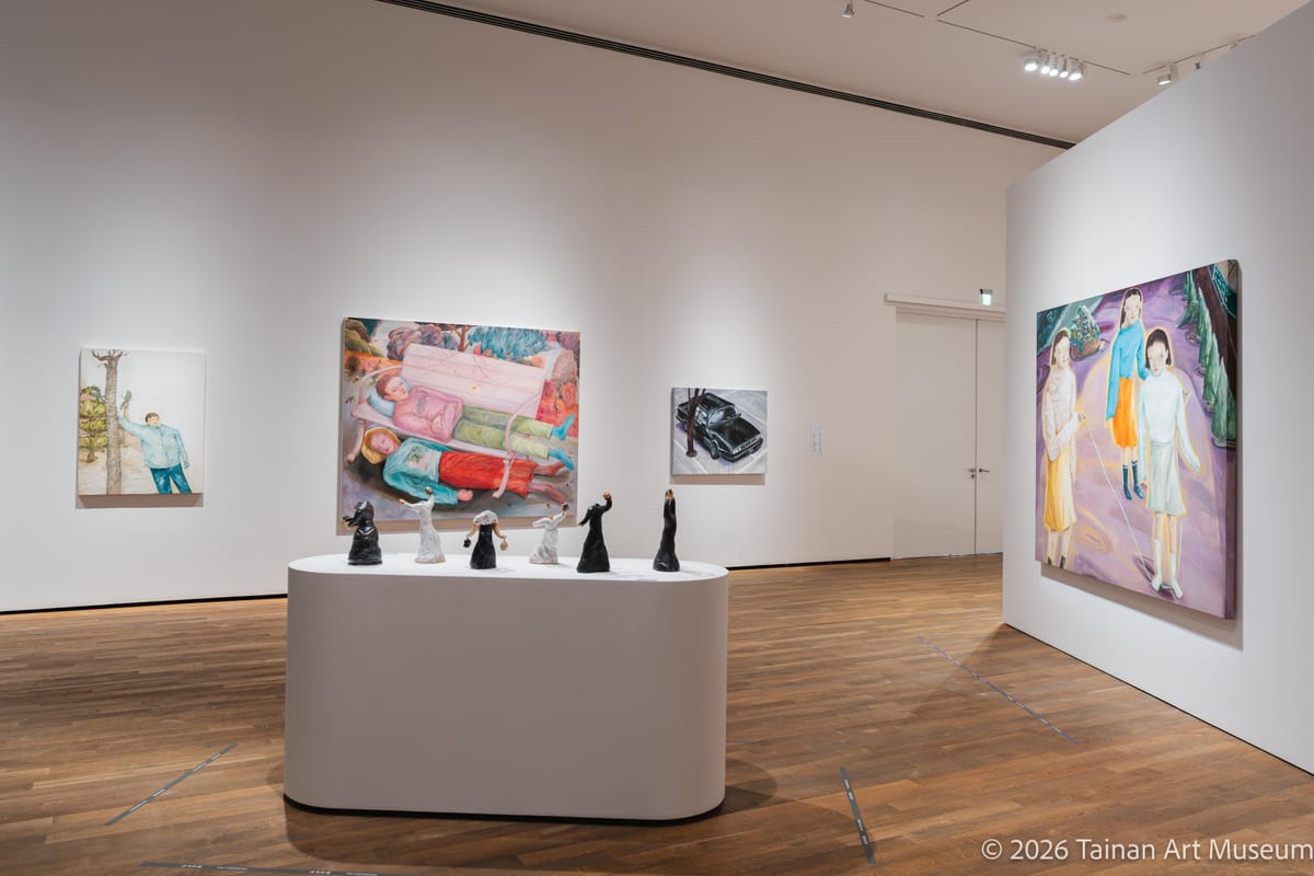 Paintings surround a central plinth holding a group of small dark objects.