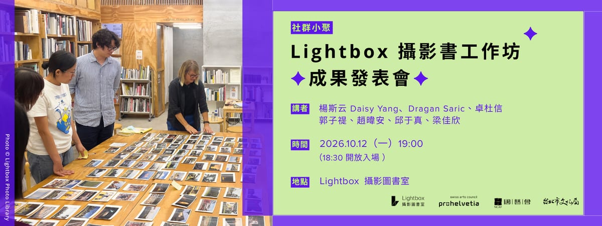People examine photographic prints spread across a wooden table at Lightbox, beside a green and purple announcement for the October 12 photography-book workshop presentations.
