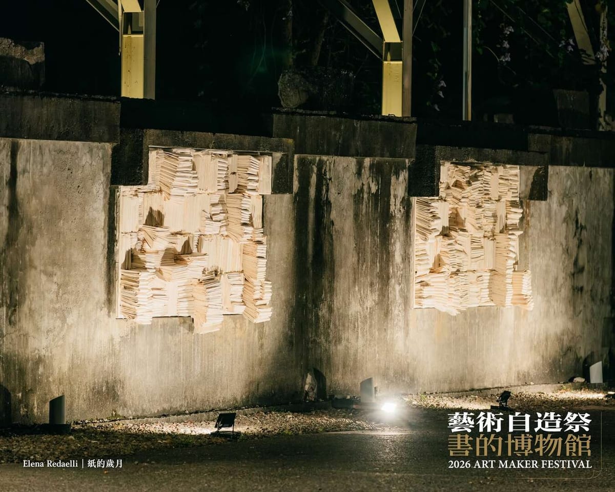 At night, two pale masses built from stacked layers of paper push out of an old concrete wall, their edges picked out by floor-mounted lights.