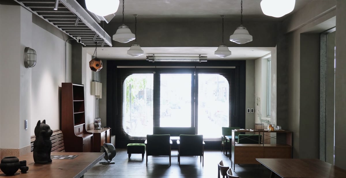 Black café chairs, white pendant lamps and a cat ornament inside MUGN.