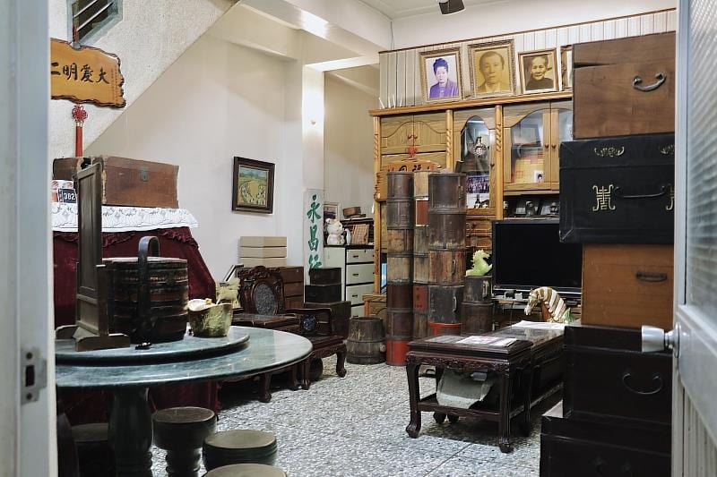 The family's living room at Yongchang, with wooden chairs, a sofa, tables and family photographs on the wall.