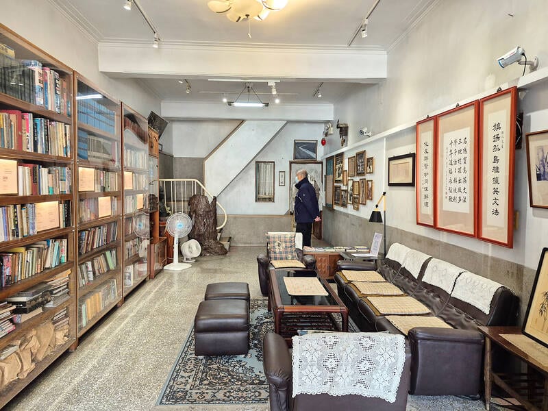 The second-floor living room at Ko Chih-hua Residence, with a wall of books beside the family's sofas, tables, calligraphy, and household furnishings.