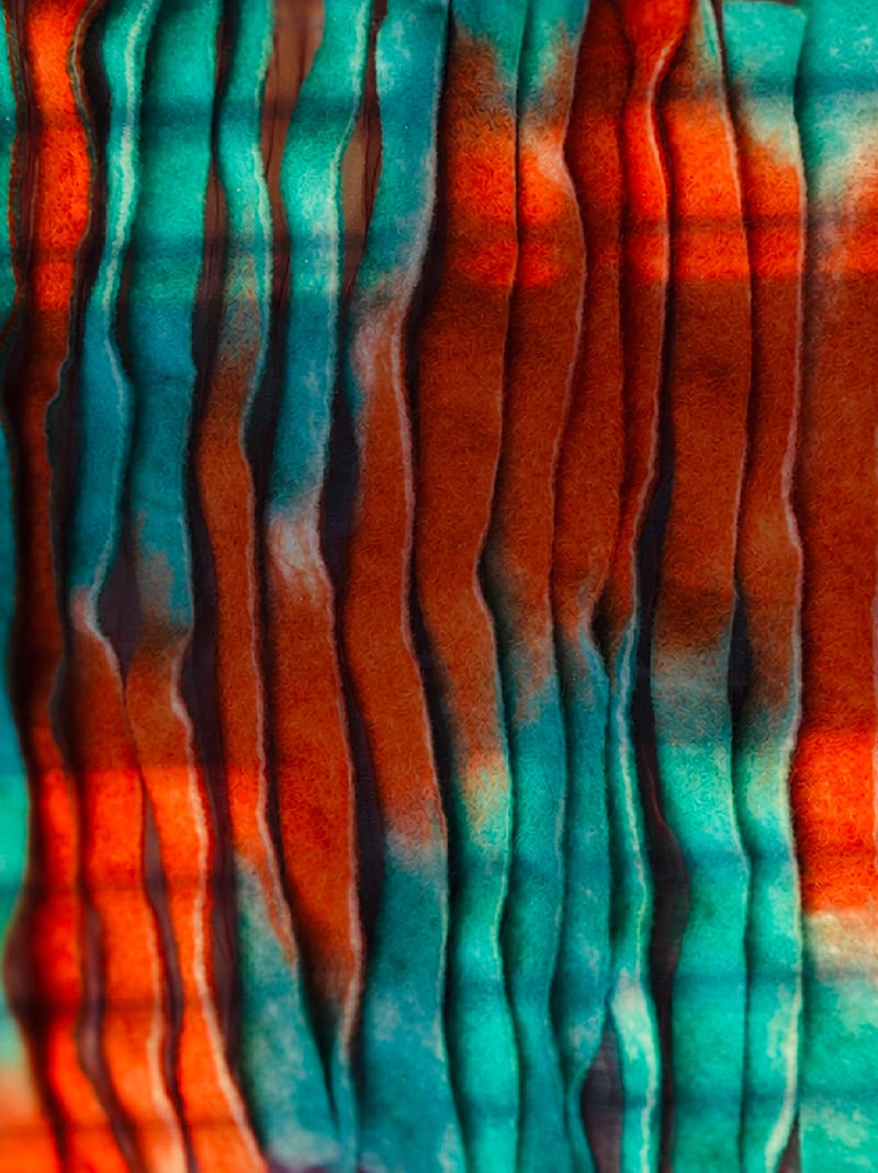 Orange, turquoise and dark brown fibres form long undulating ridges, with fuzzy surfaces and narrow ravine-like gaps.