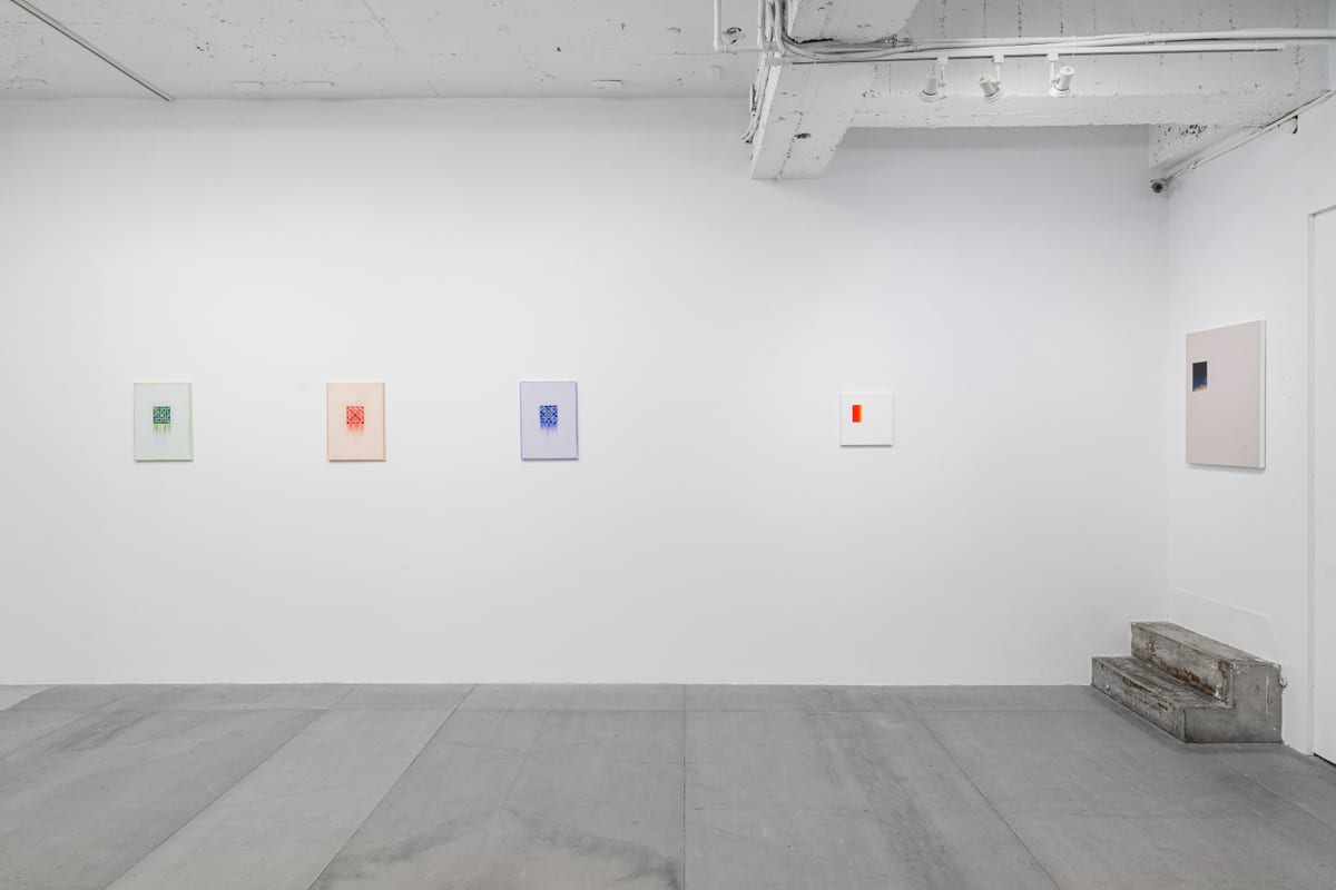 A row of small square paintings runs from green through orange-red and violet to an almost empty white, with a larger pale painting beside them.