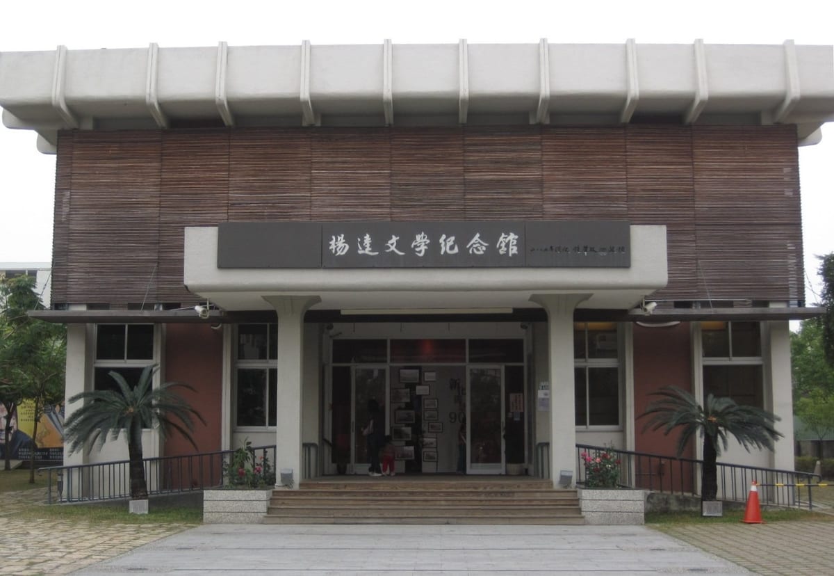 The grey modern frontage of the museum, its name mounted above the doorway with palms on either side.