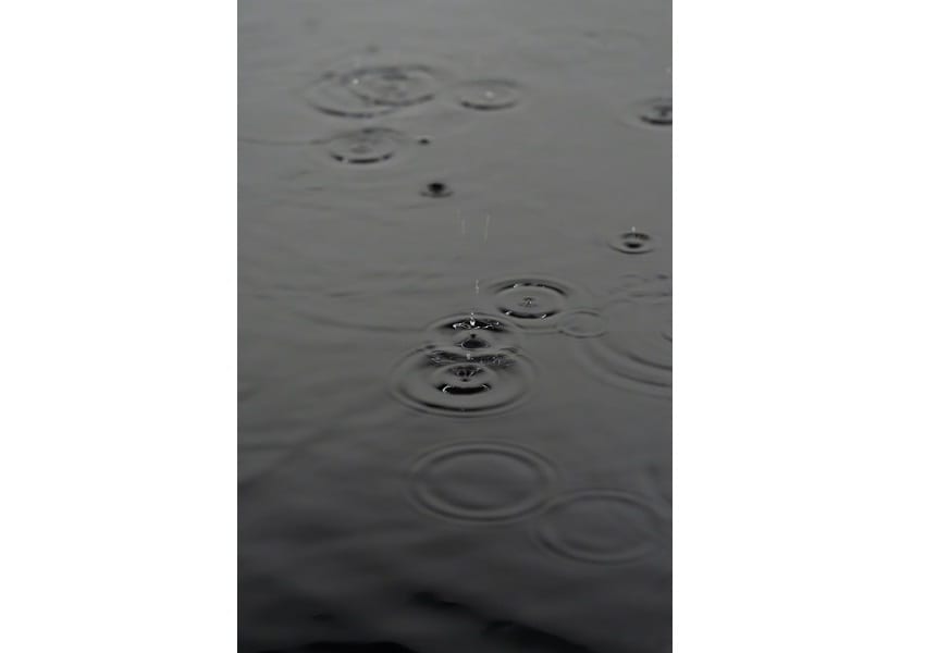 A falling drop makes circular ripples on dark water; white margins remain beside the portrait photograph.
