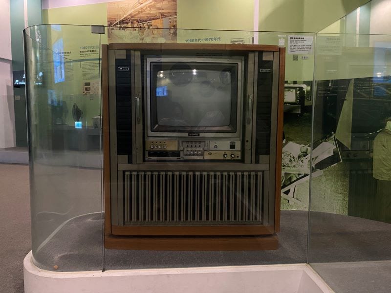 A Sampo Napoleon television behind glass, its colour picture tube housed in a large wood-coloured cabinet.